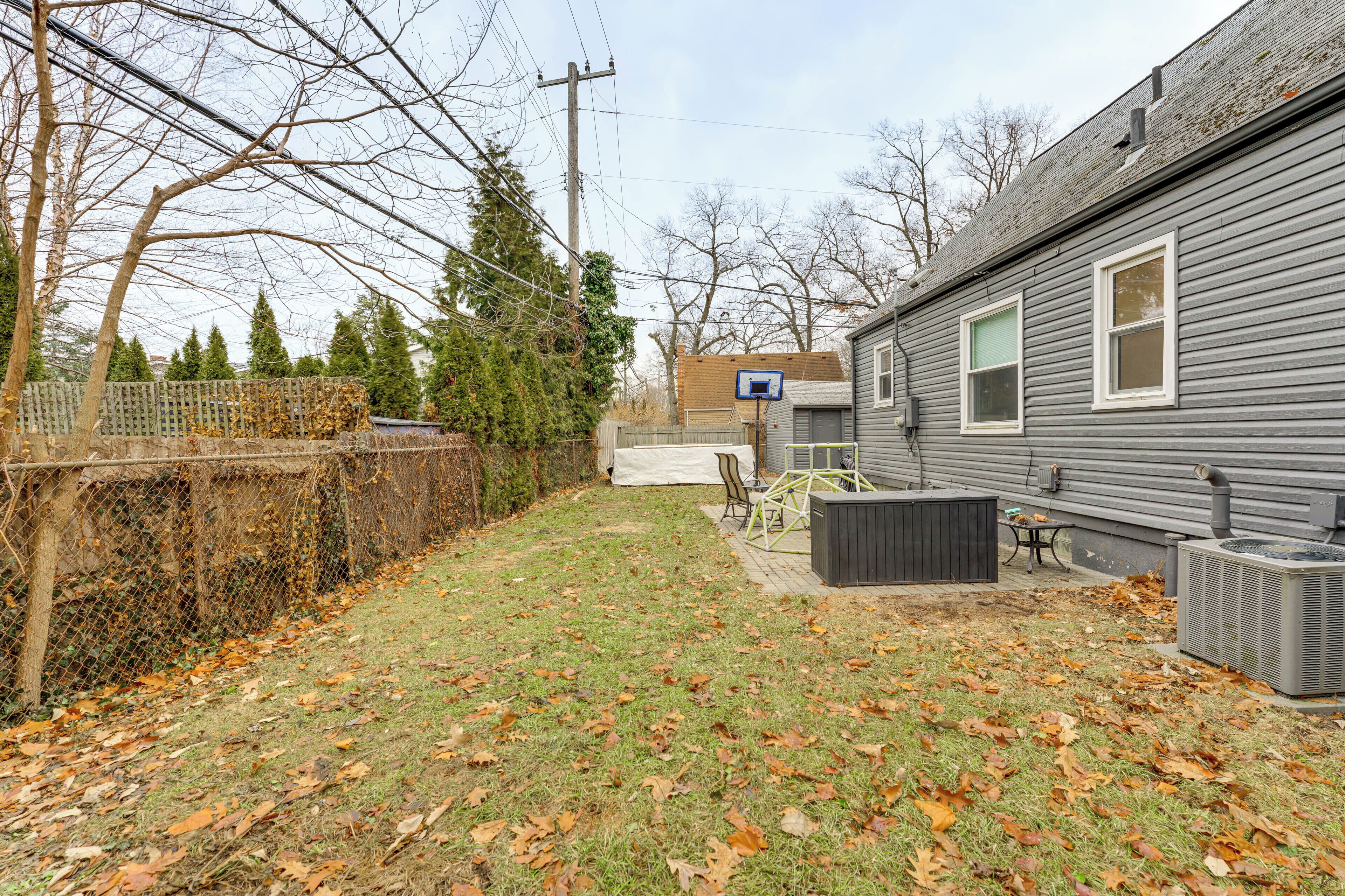 A backyard with a grill, a patio table, and a covered seating area.