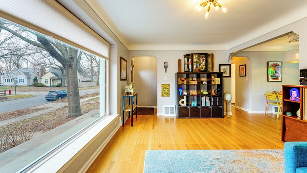 Een ruime woonkamer met houten vloeren, een groot raam en een boekenkast.