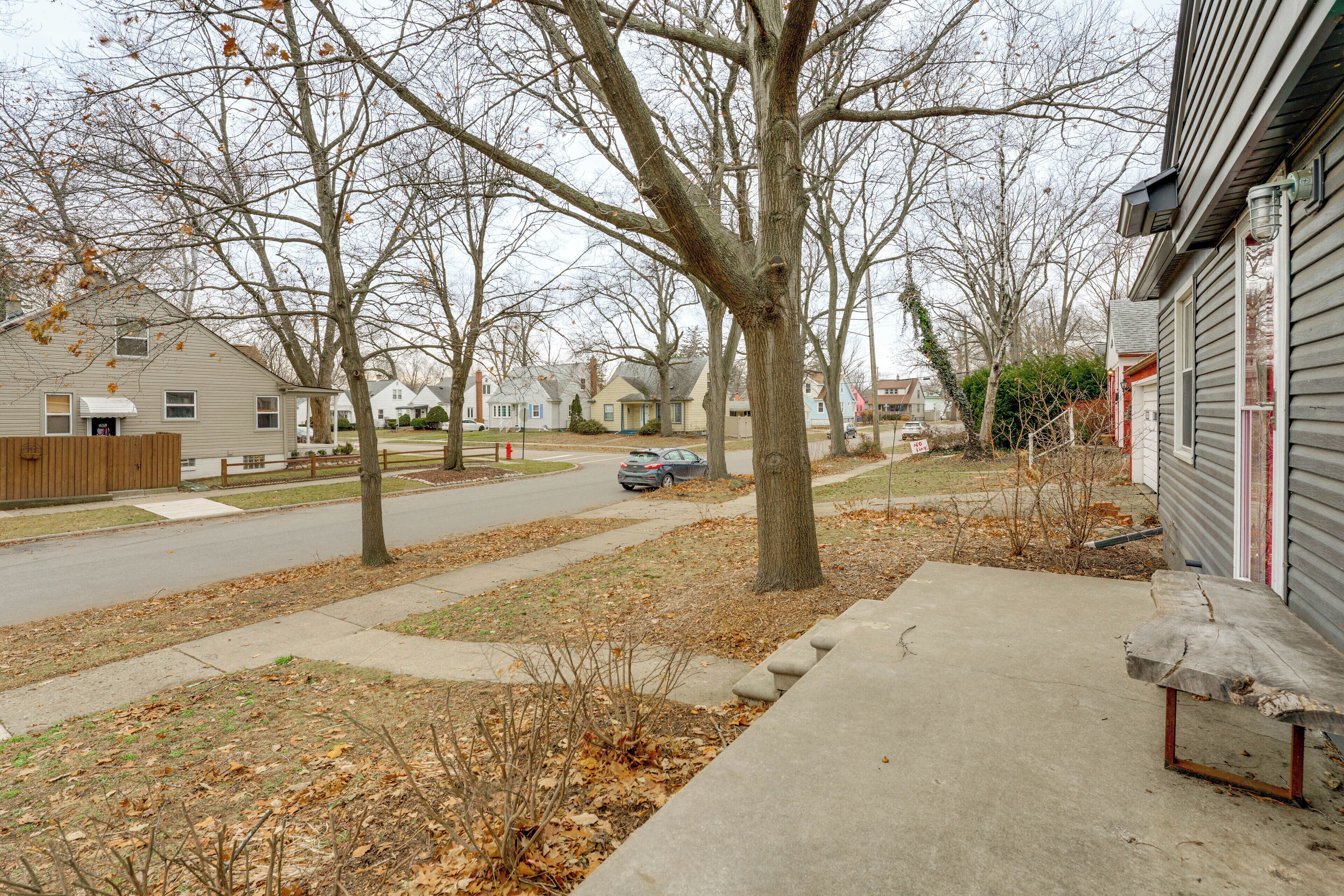 A residential street with houses, a sidewalk, and a car parked on the street.