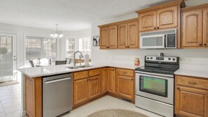 A modern kitchen with wooden cabinets, stainless steel appliances, and a large island. - 2 Mi to Pickwick Landing State Park: Home w/ Yard (Counce)