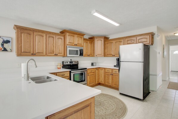 A modern kitchen with wooden cabinets, stainless steel appliances, and a white countertop. - 2 Mi to Pickwick Landing State Park: Home w/ Yard (Counce)