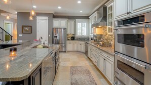 Una cocina moderna con encimeras de granito, electrodomésticos de acero inoxidable y armarios blancos.