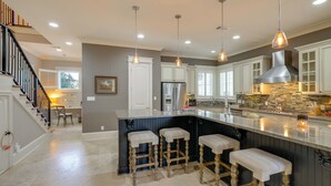 Una cocina moderna con una isla central, taburetes de bar e iluminación colgante.