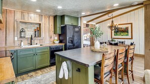A kitchen with wooden cabinets, a central island, and a dining area with chairs and a table. - 'luna Ranchhouse' Nestled Among the Pines! (Luna)