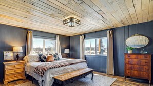 A bedroom with a wooden ceiling, a large bed with a bench, a dresser, and a mirror. - 'luna Ranchhouse' Nestled Among the Pines! (Luna)