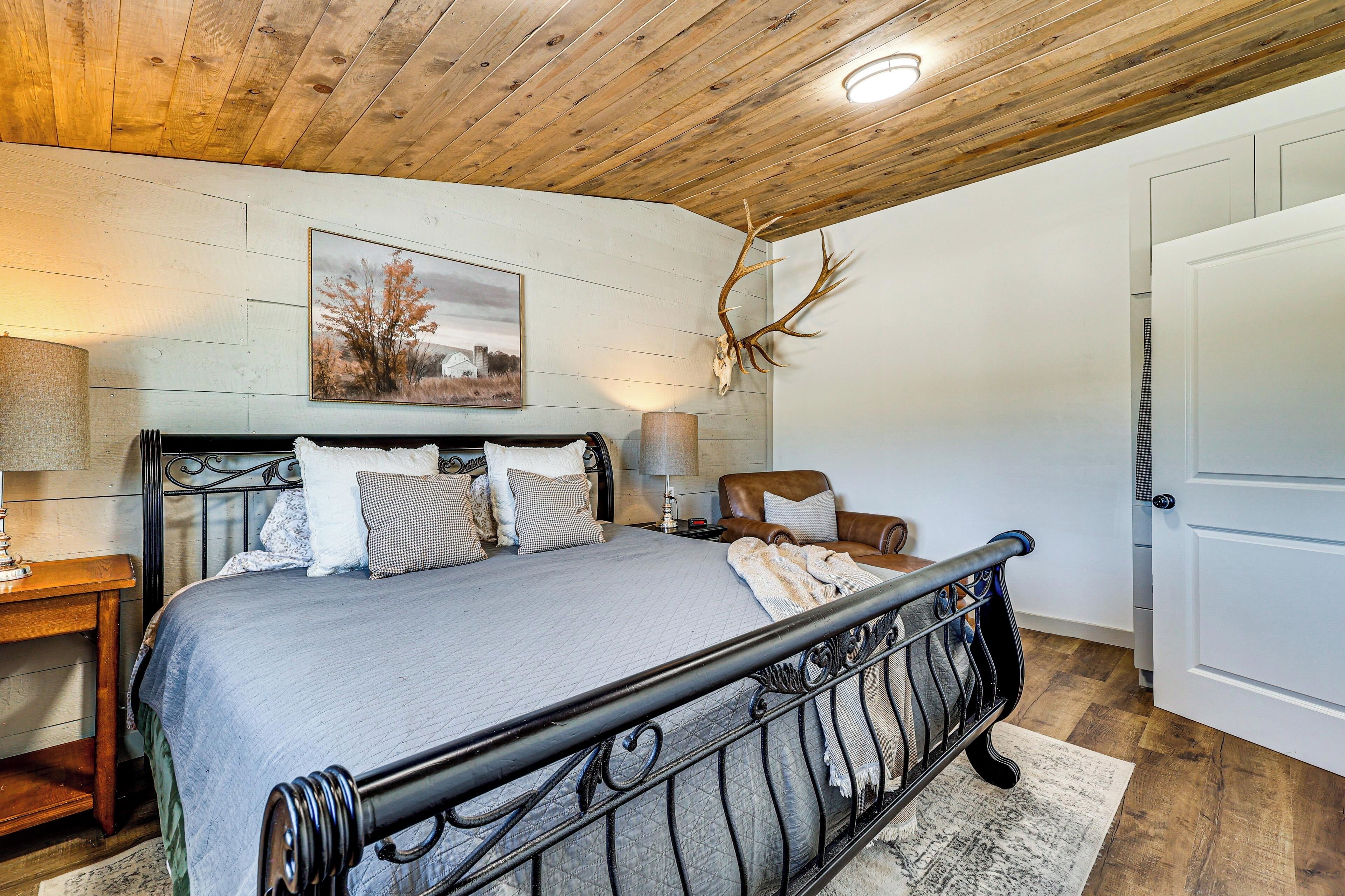 Une chambre à coucher avec un lit, une chaise, une lampe et un crâne de cerf accroché au mur.