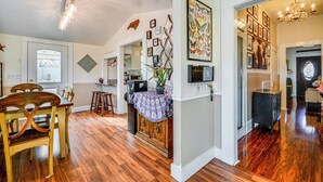 A spacious dining area with wooden chairs and a table, a kitchen with modern appliances, and a hallway leading to other rooms. - 'storybook Craftsman' Home w/ Private Hot Tub! (Mount Airy)