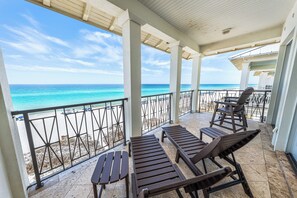 Un espacio al aire libre cubierto con sillones de descanso y vista a la playa.