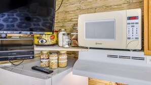 Cucina con forno a microonde, televisore e barattoli di pasta.