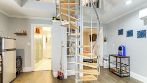 A modern kitchen with a built-in washer and dryer, a spiral staircase, and a small table with a blue object on top. - Forest-view Gem in Grantville w/ Wraparound Deck (Grantville)