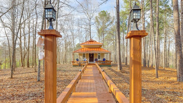 A wooden pathway leading to a small cabin with a red roof, surrounded by trees. - Forest-view Gem in Grantville w/ Wraparound Deck (Grantville)