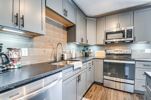 A modern kitchen with stainless steel appliances, grey cabinetry, and a wooden backsplash. - Country Setting w/ Modern Feel! Group Stay in Waco (Waco)