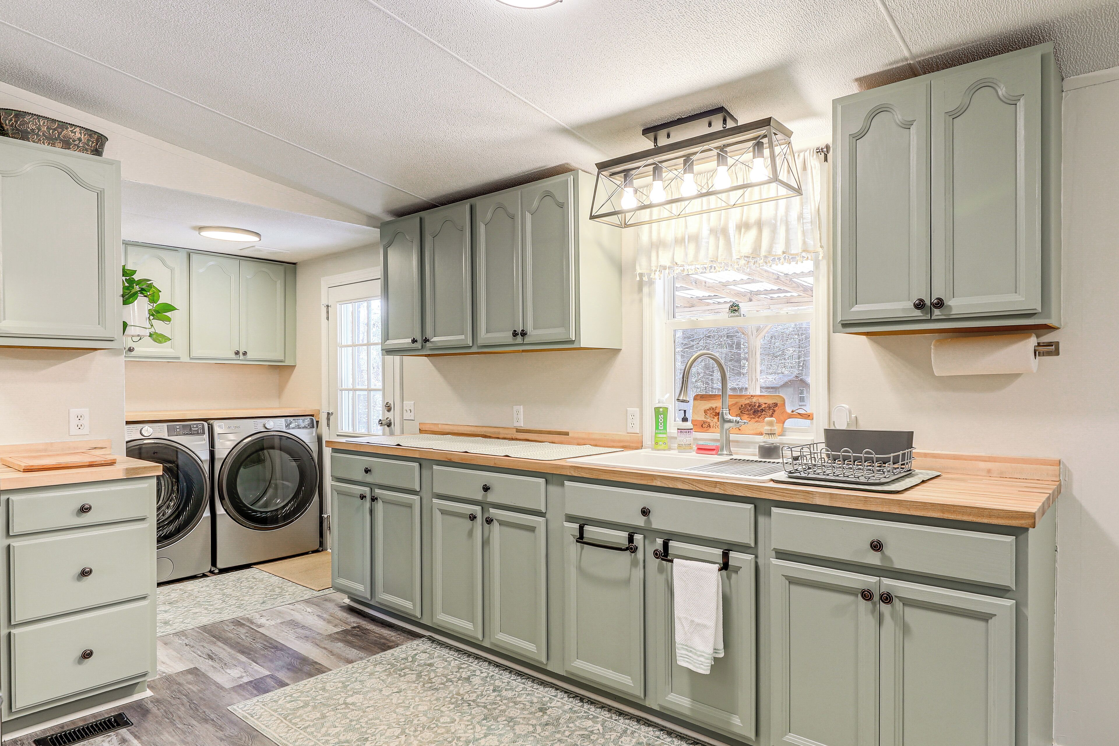 A laundry room with a washing machine, dryer, and wooden counter.