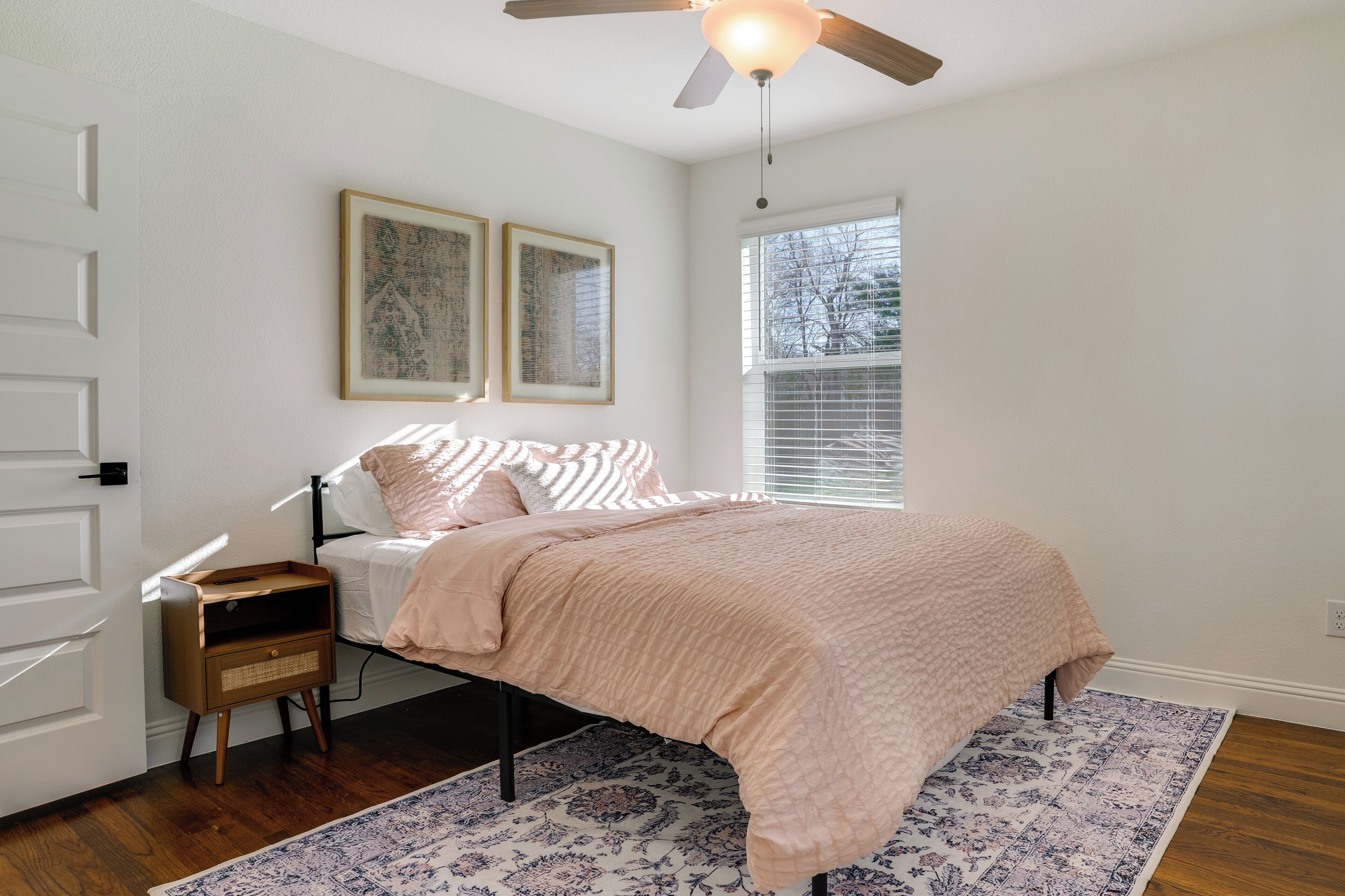 A bedroom with a bed, bedside table, and a ceiling fan.