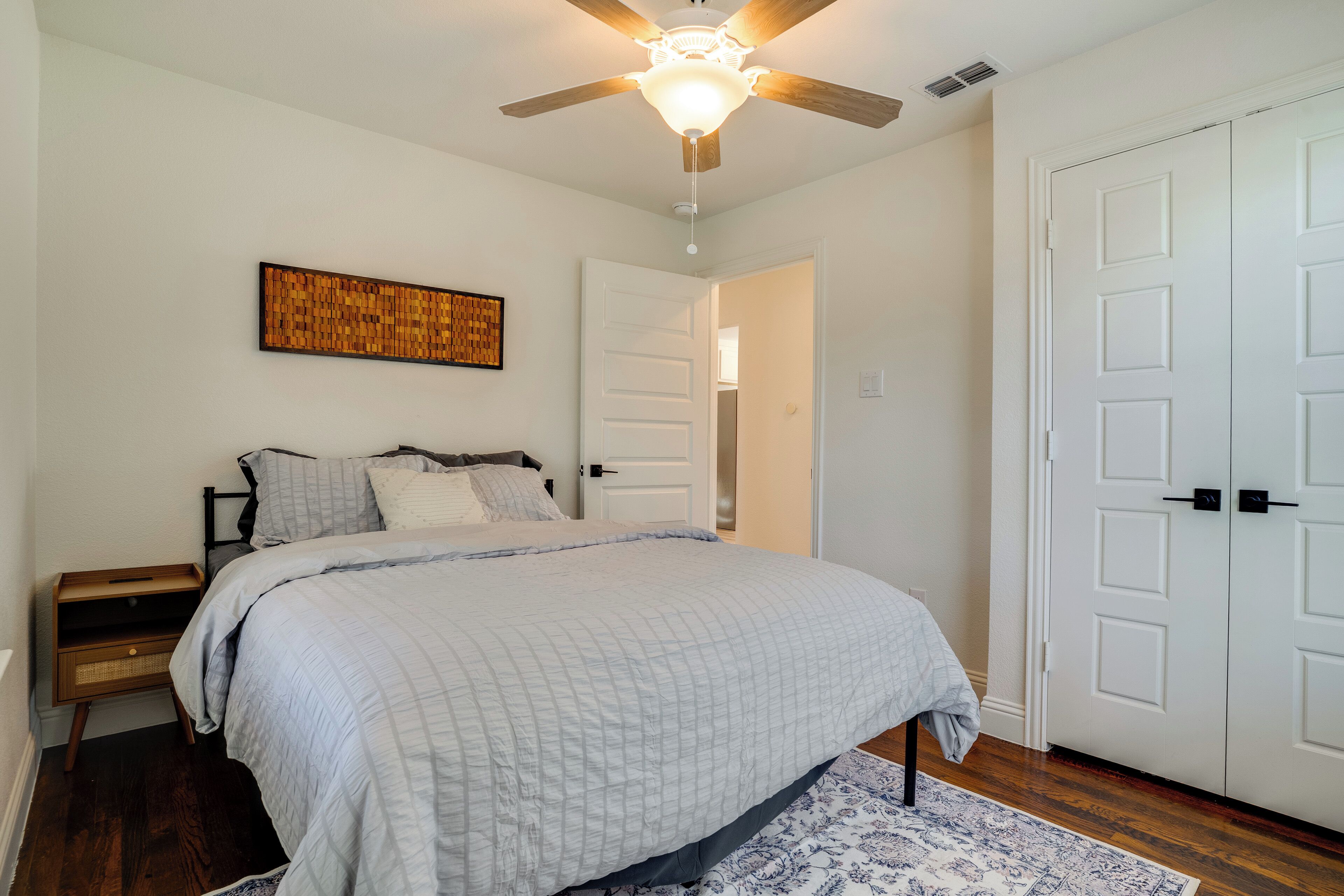 Ein Schlafzimmer mit Bett, Deckenventilator, Tür und Wandbild.