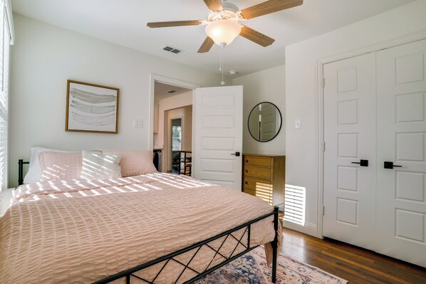 A bedroom with a bed, a ceiling fan, a door, and a wall-mounted mirror. - TCU + Game Day Home Base! 4 Mi to Dtwn Fort Worth (Fort Worth)