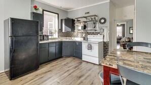 Une cuisine moderne avec des meubles de couleur sombre, un réfrigérateur noir, une cuisinière blanche et un plancher en bois.