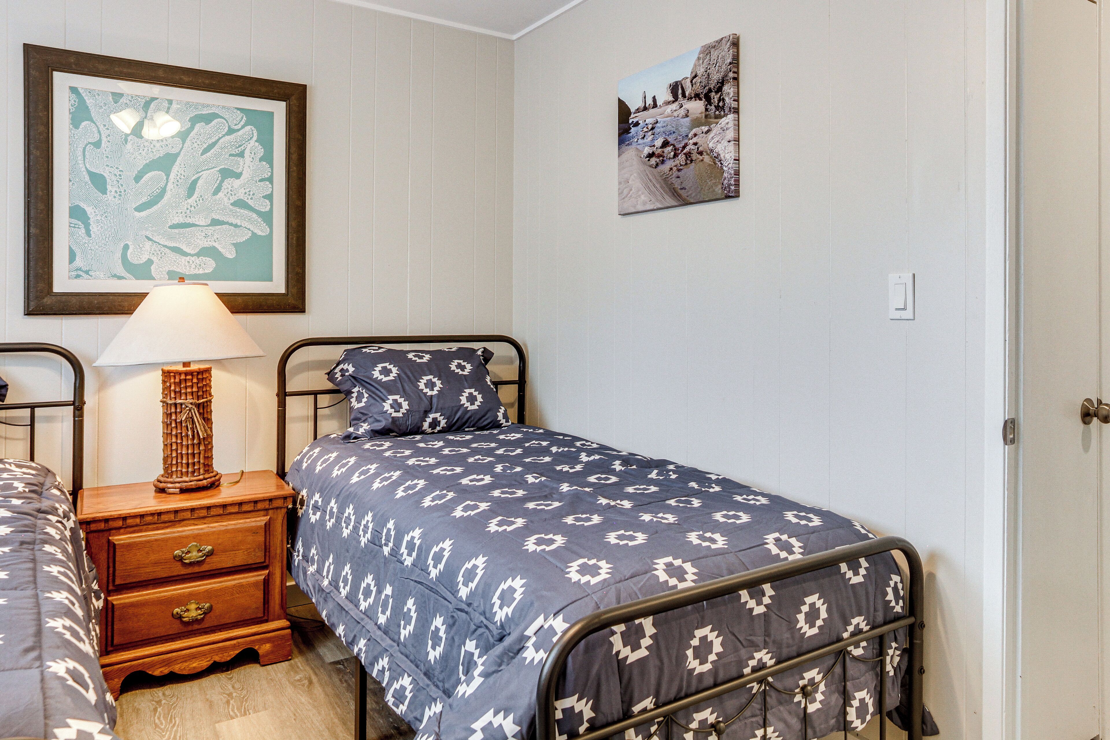 A bedroom with a single bed, a nightstand with a lamp, and a framed picture on the wall.