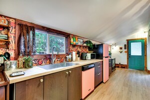 Una cocina con armarios de madera, un lavamanos, un microondas y una puerta verde azulado.