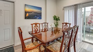 Un comedor con una mesa y sillas de madera, un jarrón con flores y un cuadro en la pared.