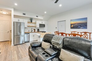 A modern kitchen with stainless steel appliances, a dining area with a black leather couch, and a large window with a scenic view. - 'the Hangar Retreat' Aviation-themed Stay in Lutz (Lutz)