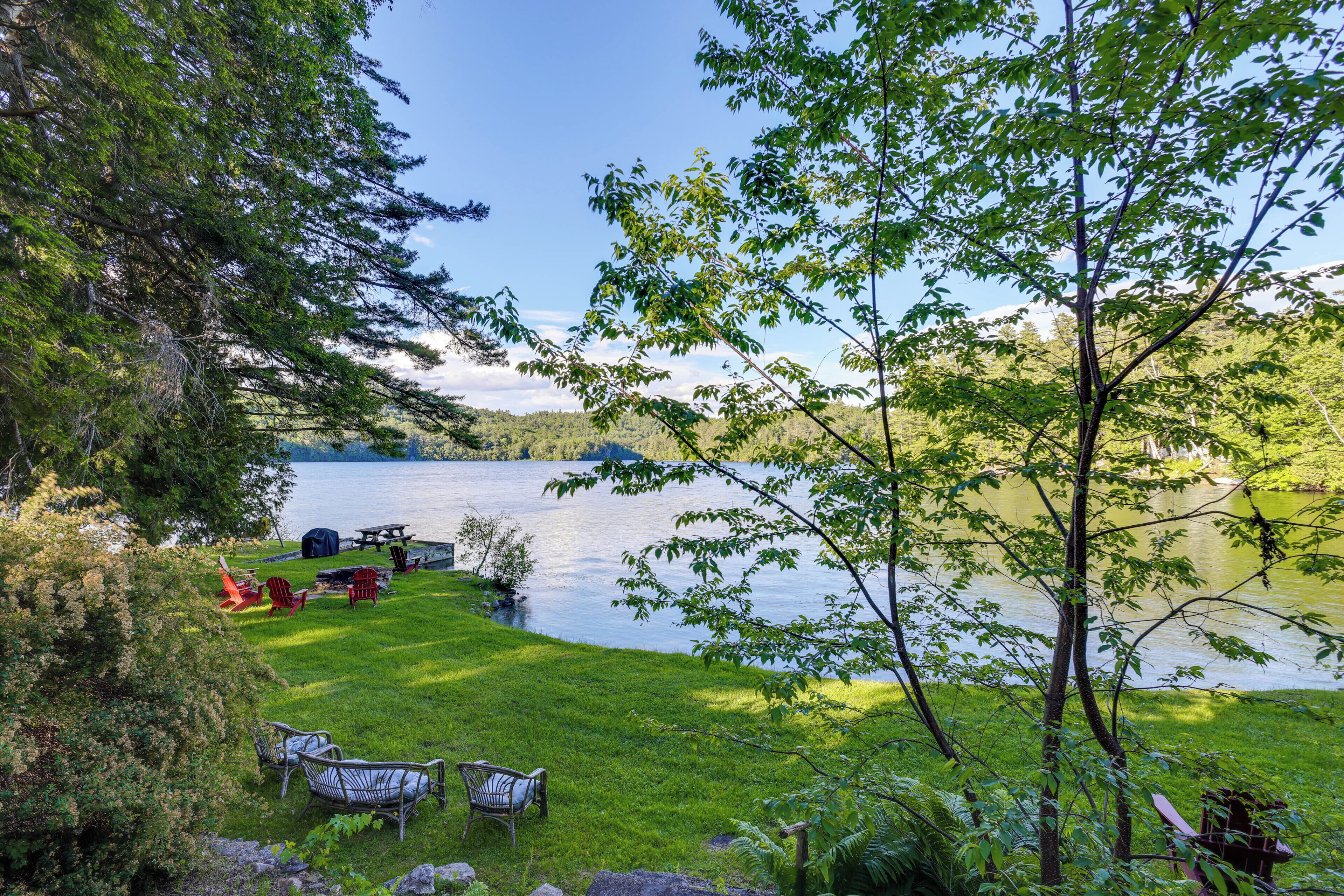 A lakeside outdoor seating area with chairs and a picnic table.