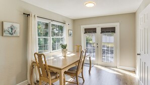 A dining area with a wooden table and chairs, a potted plant, and a view through the glass doors. - Stay & 'sea' Port Charlotte: Family Home w/ Yard (Port Charlotte)