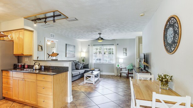 A spacious kitchen with wooden cabinets, a central island, and a dining area with white chairs. - Stay & 'sea' Port Charlotte: Family Home w/ Yard (Port Charlotte)