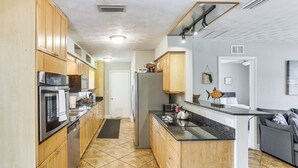 A kitchen with wooden cabinets, stainless steel appliances, and a black countertop island. - Stay & 'sea' Port Charlotte: Family Home w/ Yard (Port Charlotte)