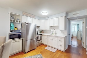 Una cocina moderna con armarios blancos, electrodomésticos de acero inoxidable y piso de madera.
