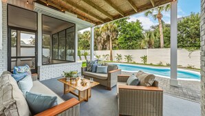 Una zona relax all'aperto riparata, con mobili in rattan, una piscina e vista sulle palme.