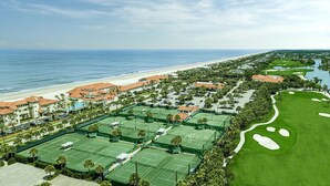 Un campo de golf con varias canchas de tenis, una playa y un puerto deportivo.