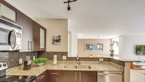 Una cocina moderna con armarios de madera oscura, un lavamanos de acero inoxidable y un lavavajillas empotrado.