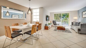 Una sala de estar moderna con comedor, ventanas amplias y un sofá gris.