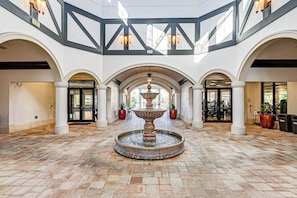 A spacious lobby with a central fountain, arched doorways, and a high ceiling with exposed beams. - 8 Mi to Dtwn Naples: Condo w/ Resort Amenities! (Naples)