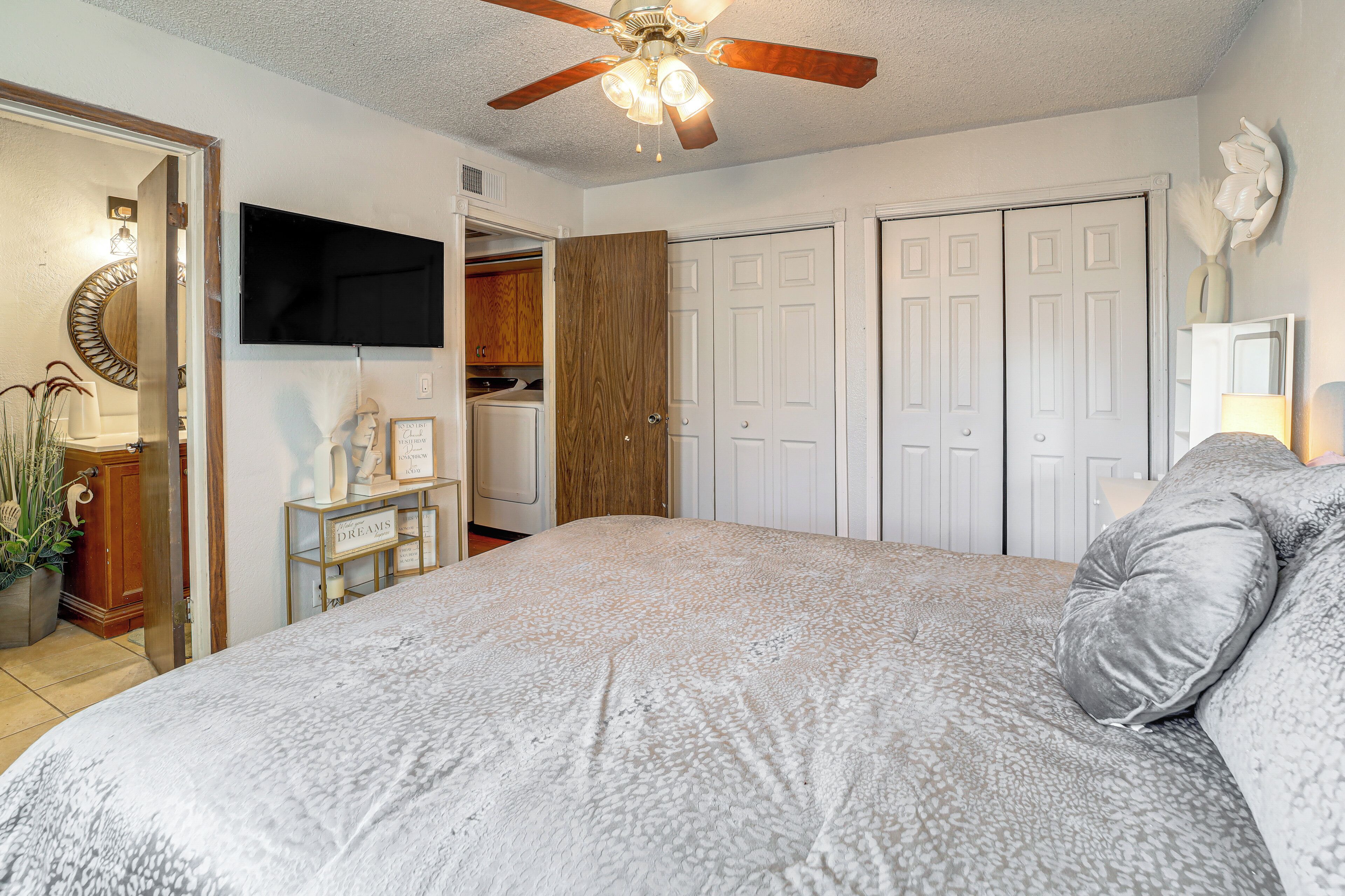A bedroom with a bed, a ceiling fan, a TV, and a wardrobe.