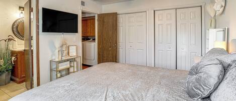 A bedroom with a bed, a ceiling fan, a TV, and a wardrobe.