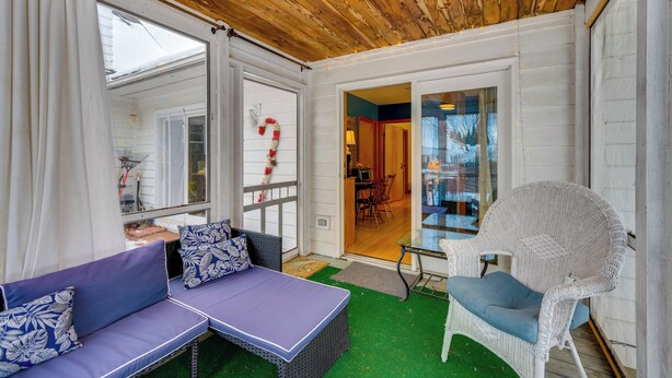A covered patio with a wooden ceiling, a white wicker chair, a purple sofa, and a glass door leading to an indoor area. - 2 Mi to Main Street! Cozy Burlington Guest Suite (Burlington)