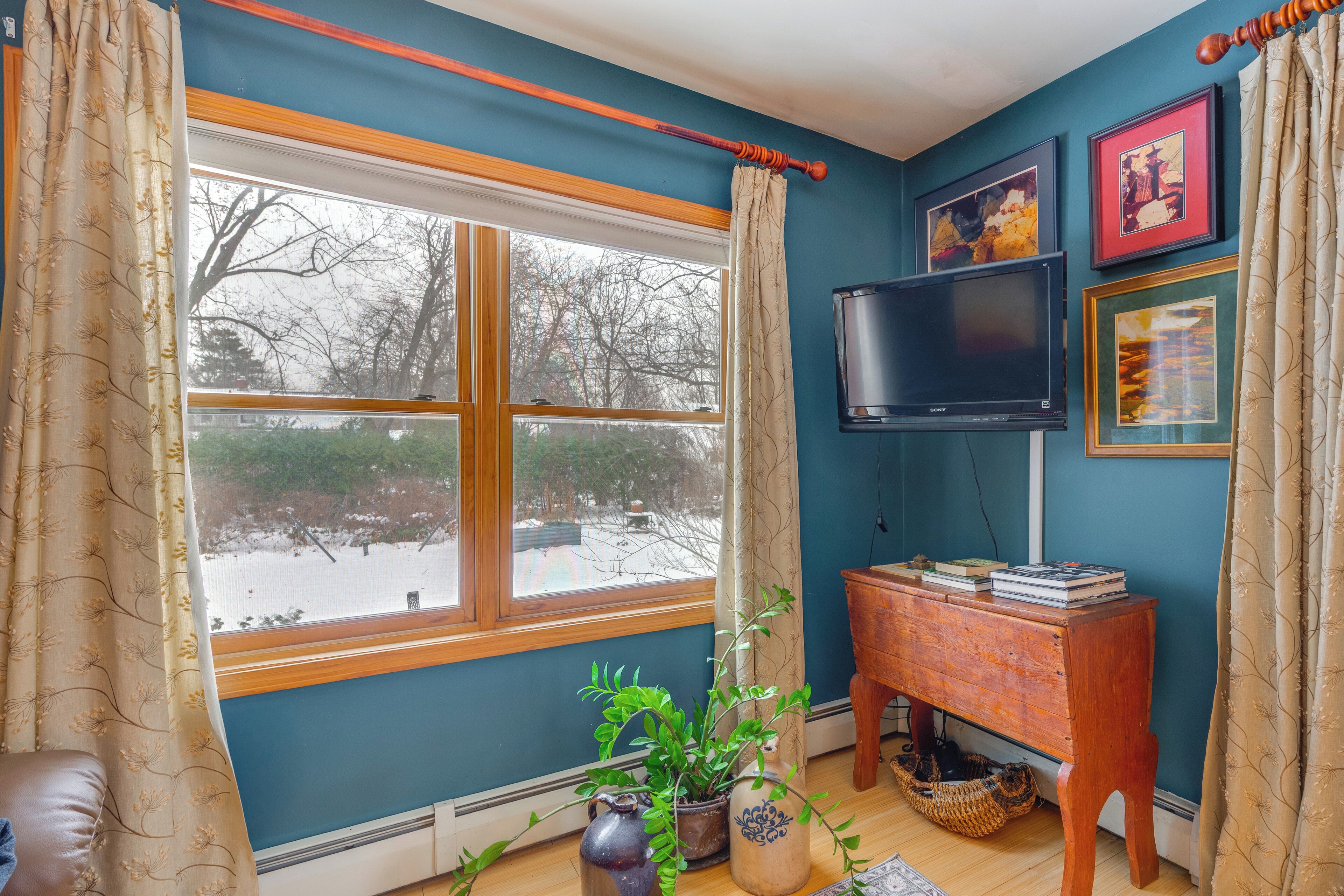 Una sala de estar con un ventanal grande, un televisor y un mueble de madera.