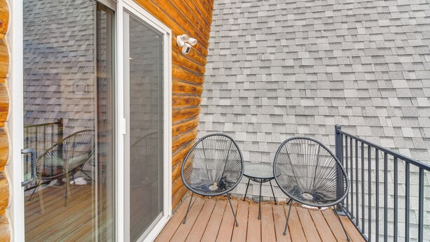 A wooden deck with two metal chairs and a glass door leading to a patio area. - Wooded Retreat w/ Private Hot Tub in Evergreen (Evergreen)