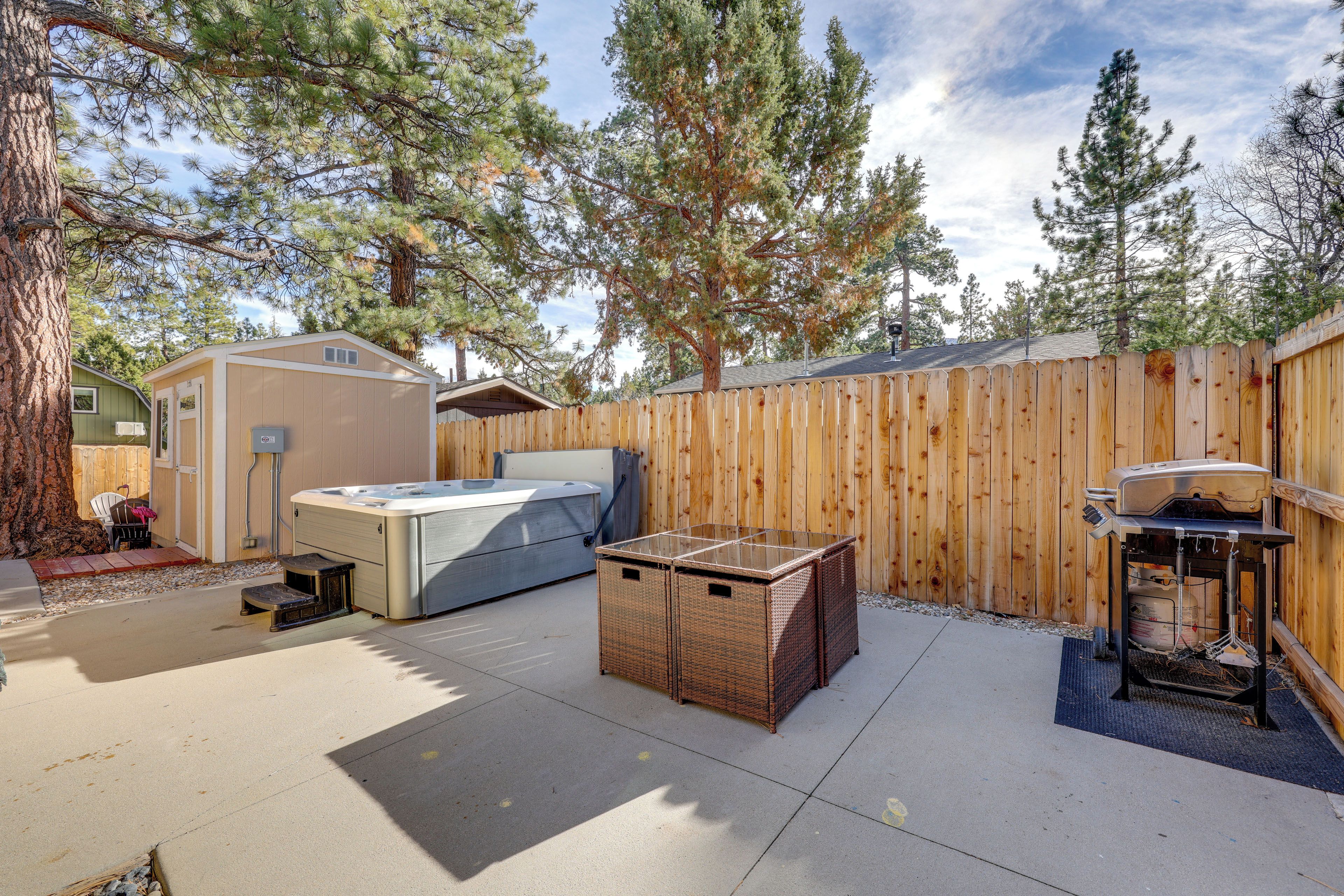 A backyard with a hot tub, a barbecue grill, and a shed.
