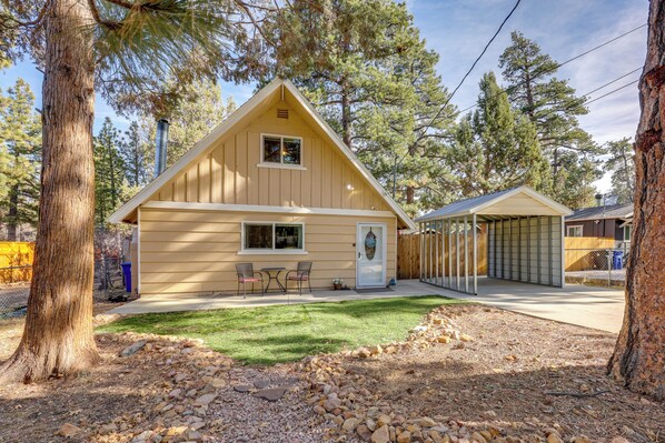 A two-story wooden cabin with a covered porch, a small patio, and a well-maintained lawn. - Hot Tub + Game Room: Group Getaway in Big Bear! (Sugarloaf)