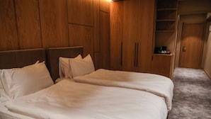 Une chambre d’hôtel avec deux lits, une armoire en bois et une petite table de chevet.