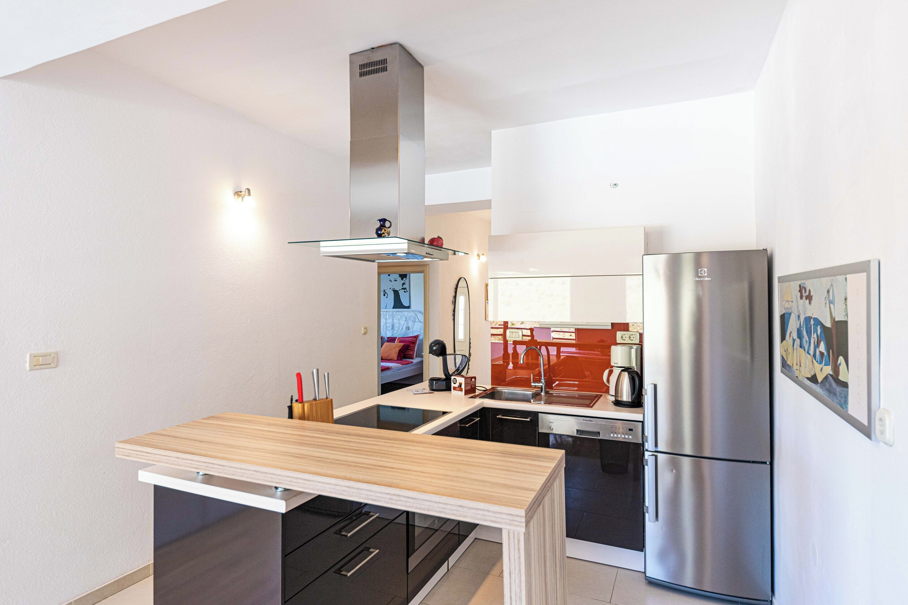 Una cocina moderna con una isla central, electrodomésticos de acero inoxidable y vista al área de estar contigua.