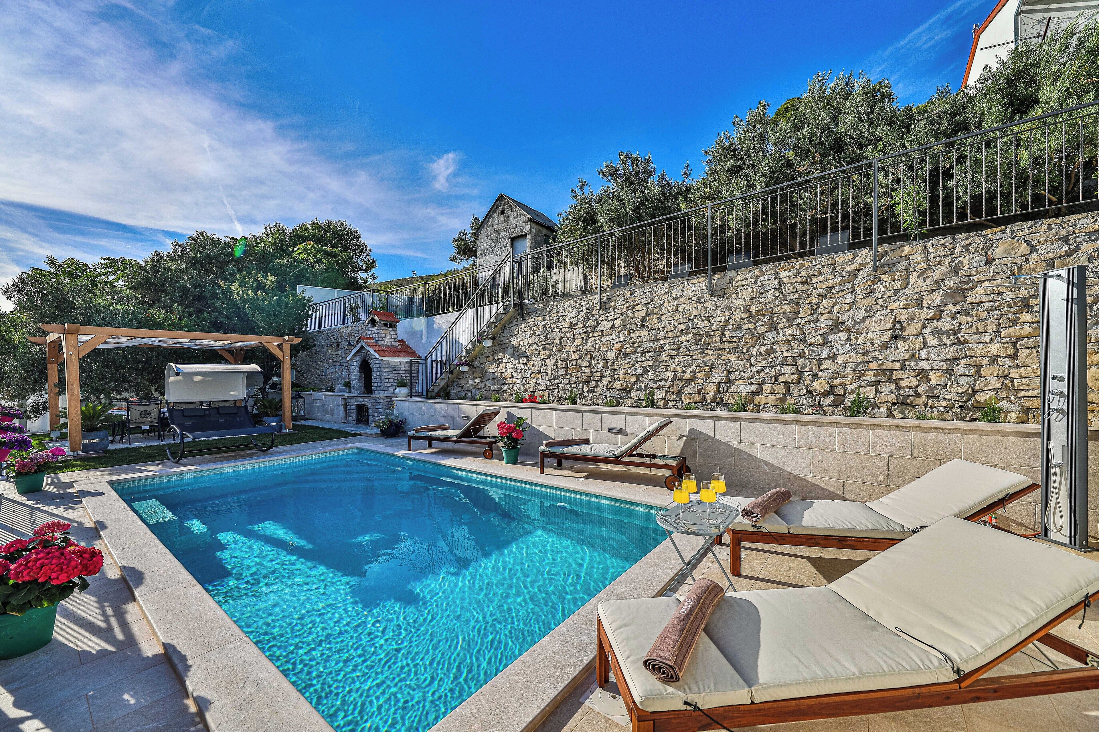 Une piscine avec des chaises longues et un espace barbecue.
