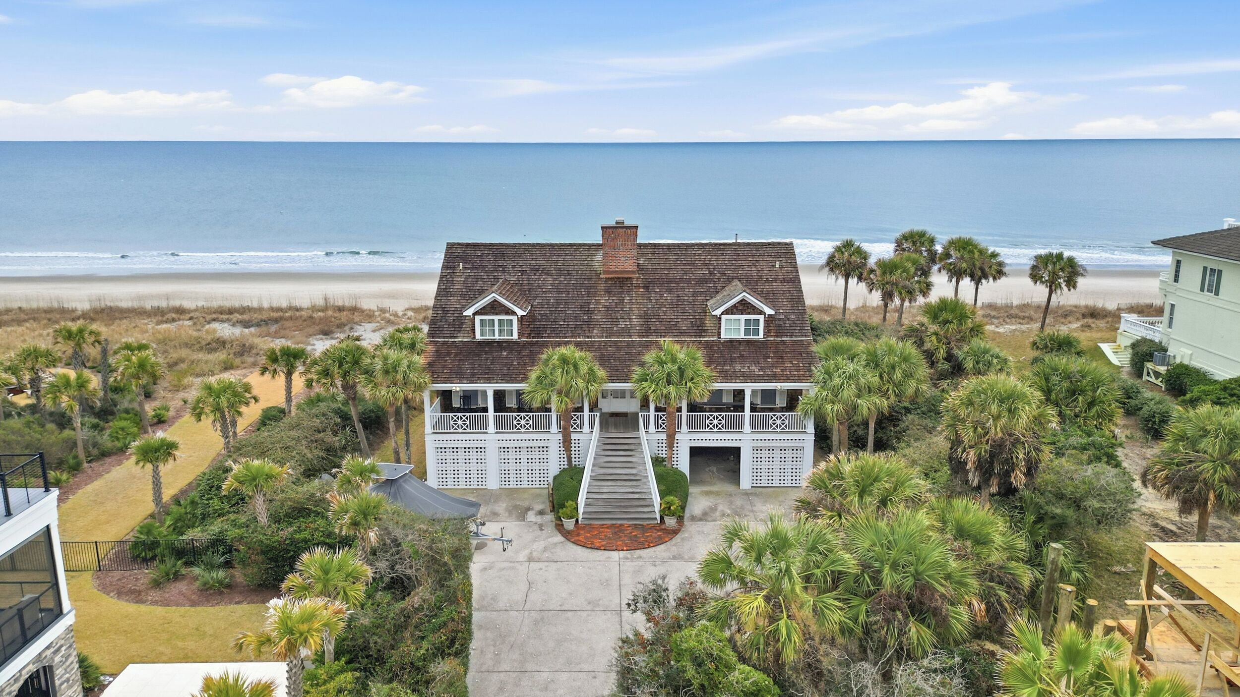 Une maison située en bord de mer, dotée d’un balcon, d’un porche et offrant une vue sur l’océan.