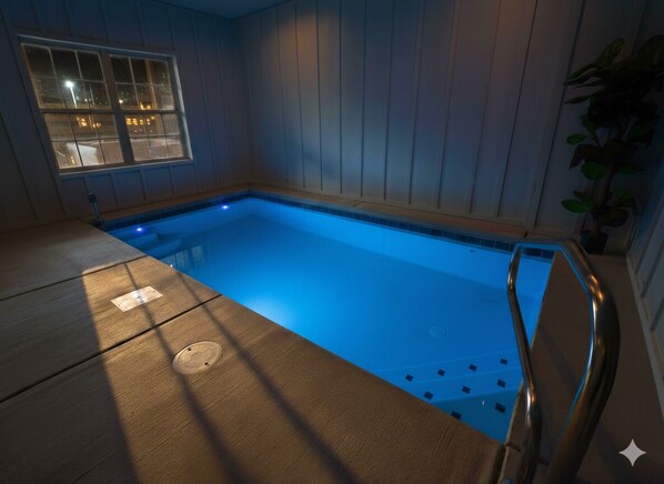 A swimming pool with a wooden deck and a window with a view of the outside. - Heated indoor pool | Hot tub | Game Room (Sevierville)