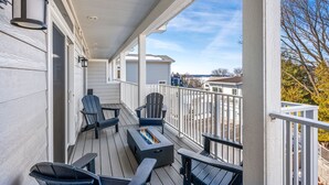 Een overdekt terras met Adirondack-stoelen, een vuurkorf en uitzicht op de omgeving.