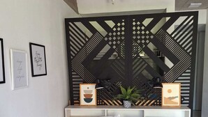 Een moderne slaapkamer met een bed, een decoratieve zwarte scheiding en lijstwerken aan de muur.