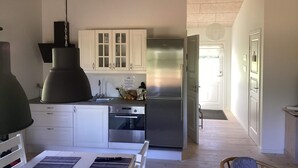 A modern kitchen with white cabinets, a stainless steel refrigerator, and a large pendant light. - 5 Star Holiday Home in Ansager (Ansager)